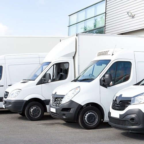 Several cars vans trucks parked in parking lot for rent or delivery